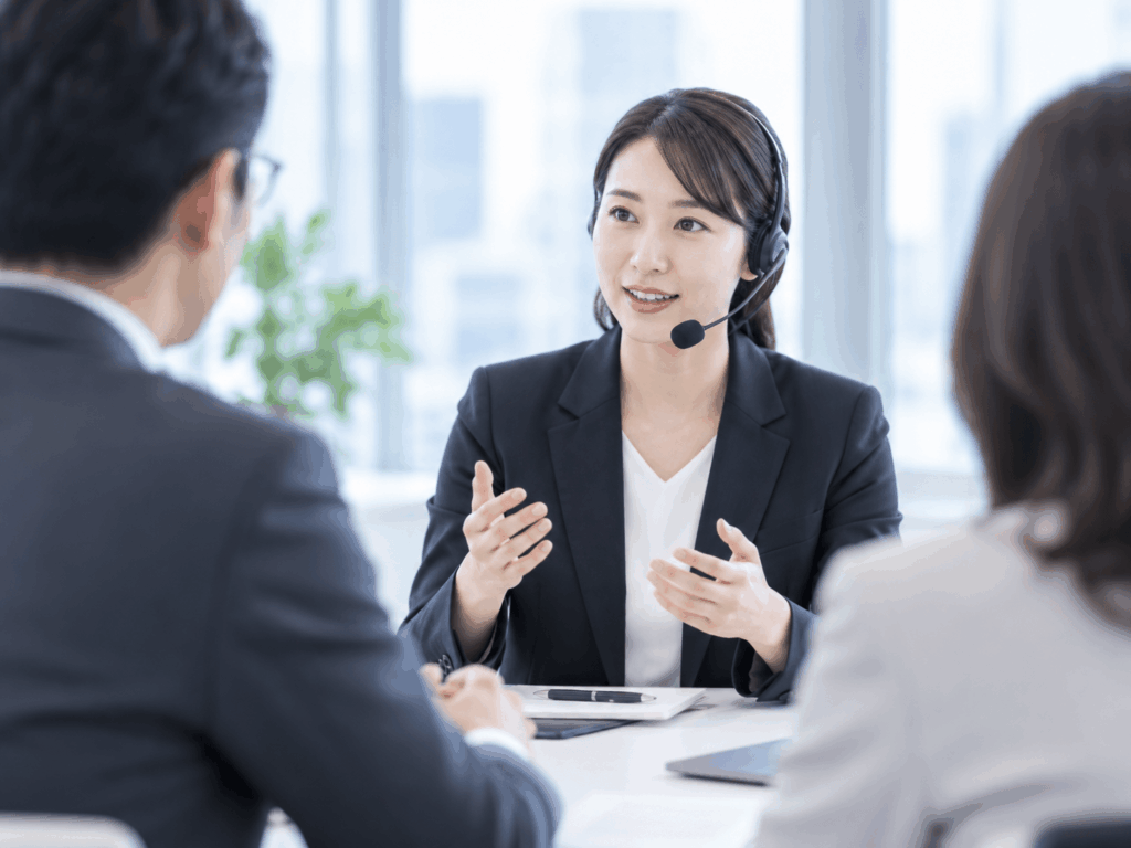 ヘッドセットを着けた女性が会議の参加者と話す様子